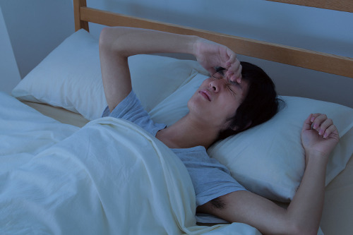 ベットで顔を曇らせる男性